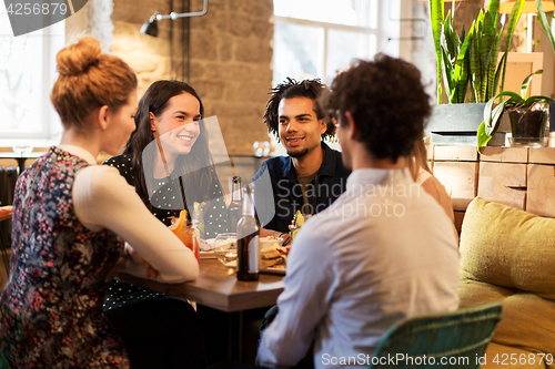 Image of happy friends eating and drinking at bar or cafe