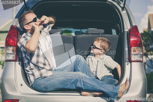 Image of Happy father and son getting ready for road trip on a sunny day