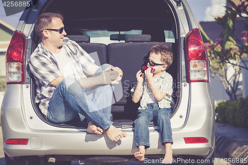 Image of Happy father and son getting ready for road trip on a sunny day