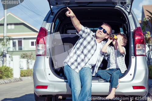 Image of Happy father and son getting ready for road trip on a sunny day