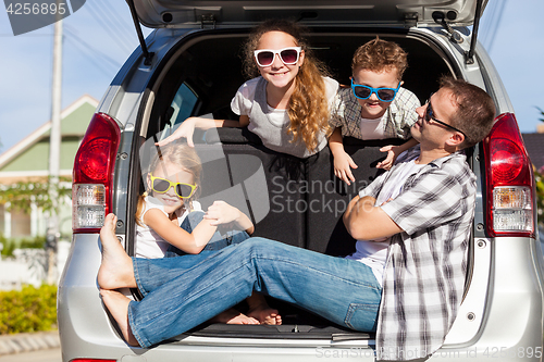 Image of Happy family getting ready for road trip on a sunny day.