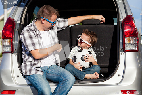 Image of Happy father and son getting ready for road trip on a sunny day.