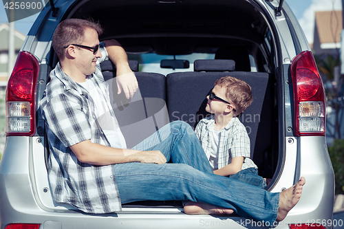 Image of Happy father and son getting ready for road trip on a sunny day