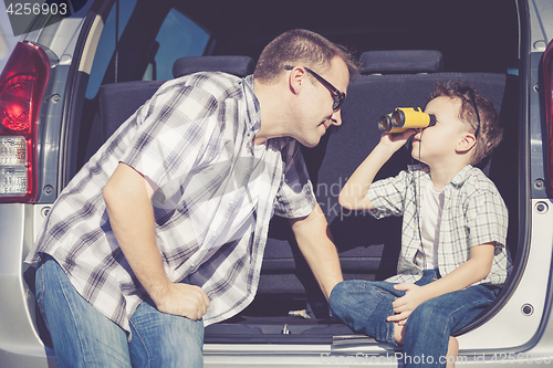 Image of Happy father and son getting ready for road trip on a sunny day