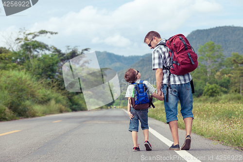 Image of Father and son walking on the road. 