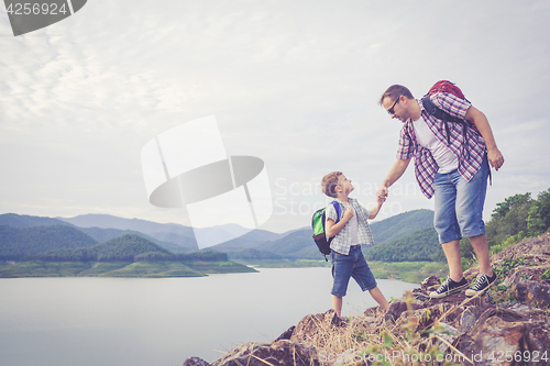 Image of Father and son standing near the lake.