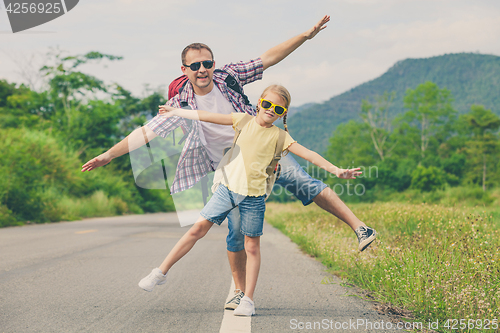 Image of Father and daughter walking on the road.