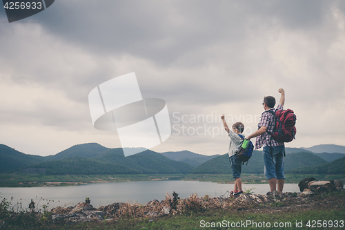 Image of Father and son standing near the lake.