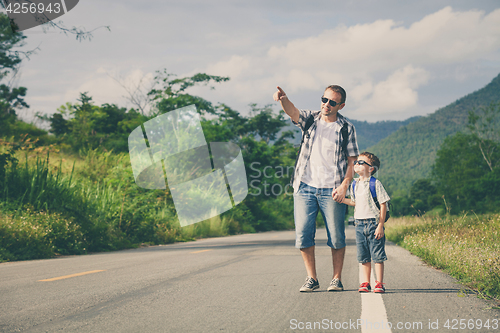 Image of Father and son walking on the road.
