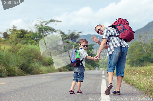 Image of Father and son walking on the road.