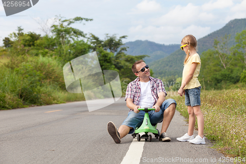 Image of Father and daughter playing on the road.