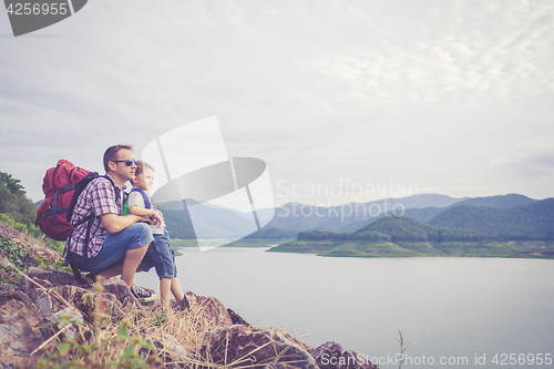 Image of Father and son standing near the lake.