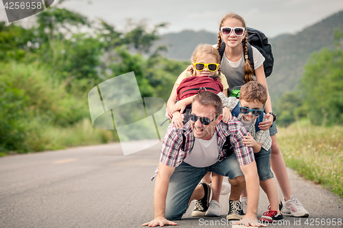 Image of Father and children walking on the road.