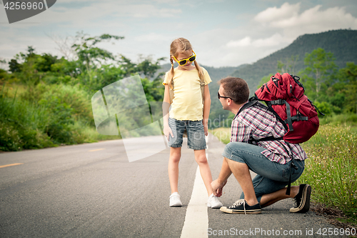Image of Father and daughter walking on the road.