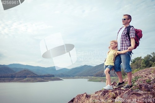 Image of Father and son standing near the lake.