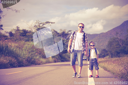 Image of Father and son walking on the road.