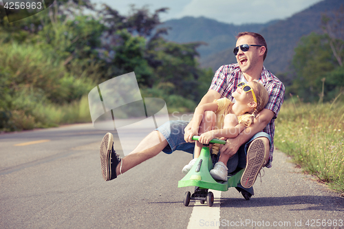 Image of Father and daughter playing on the road.