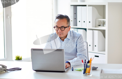Image of businessman in eyeglasses with laptop office