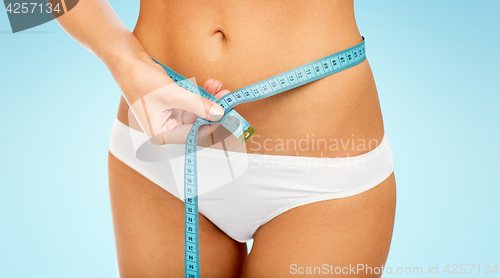 Image of close up of woman body with measure tape on waist