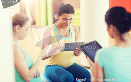 Image of happy pregnant women with gadgets in gym