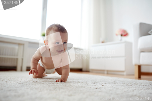 Image of little baby in diaper crawling on floor at home