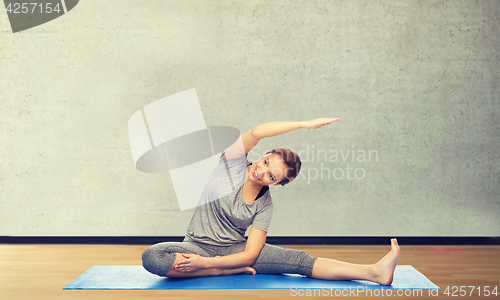 Image of happy woman making yoga and stretching on mat