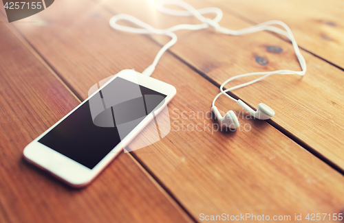 Image of close up of blank smartphone and earphones on wood