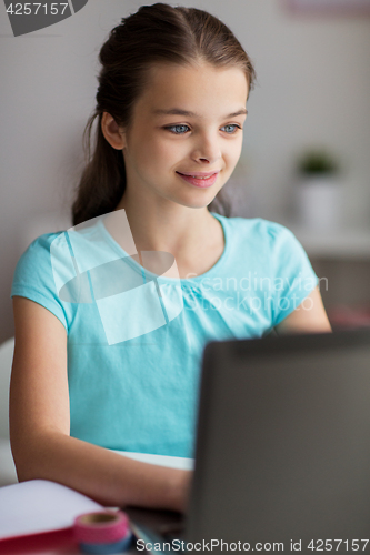 Image of happy girl typing on laptop at home