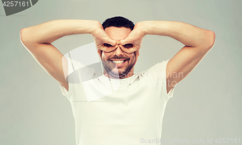 Image of man making finger glasses over gray background