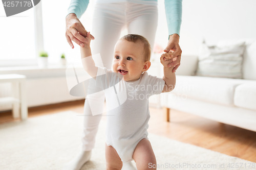 Image of happy baby learning to walk with mother help