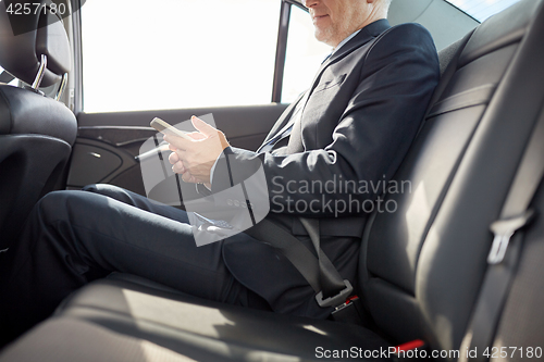 Image of senior businessman texting on smartphone in car