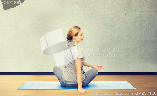 Image of woman making yoga in twist pose on mat