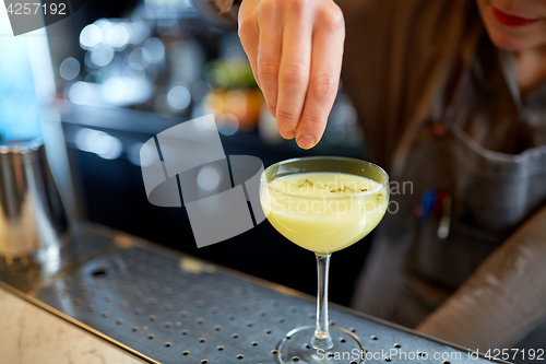 Image of bartender with glass of cocktail at bar