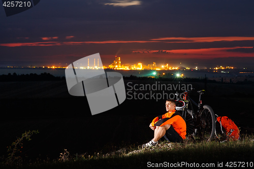 Image of Biker resting on top of mountain with his bicycle