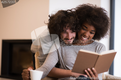 Image of multiethnic couple hugging in front of fireplace