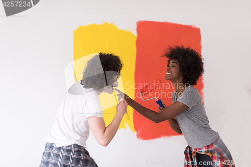 Image of multiethnic couple painting interior wall