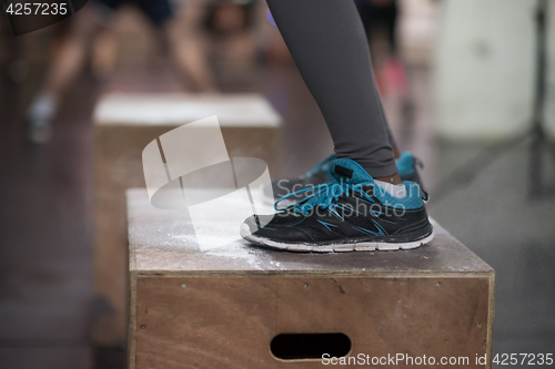 Image of black woman is performing box jumps at gym