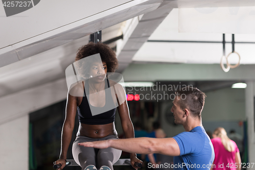 Image of black woman doing parallel bars Exercise with trainer