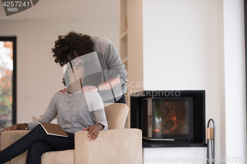 Image of multiethnic couple hugging in front of fireplace