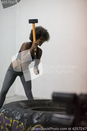 Image of black woman workout with hammer and tractor tire