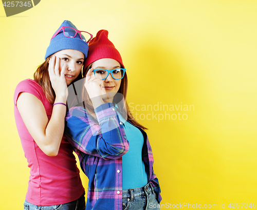 Image of lifestyle people concept: two pretty young school teenage girls having fun happy smiling on yellow background 