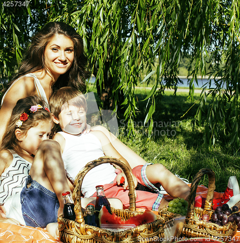 Image of cute happy family on picnic laying on green grass mother and kid