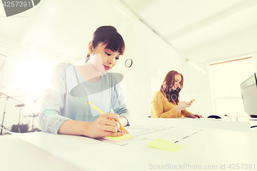 Image of architect woman with blueprint writing at office