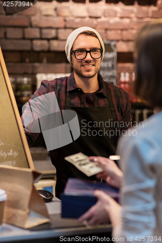 Image of happy barman and woman paying money at cafe