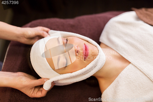 Image of woman having face massage with towel at spa