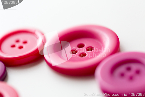 Image of red and pink sewing buttons on white background