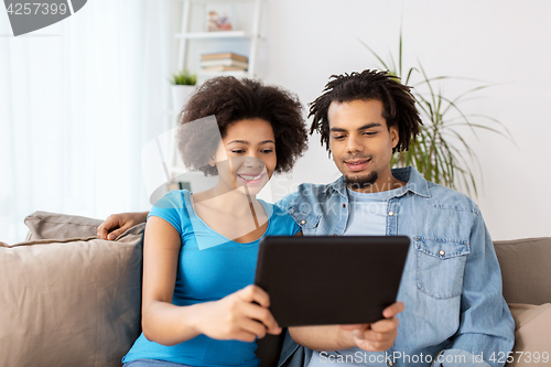 Image of smiling happy couple with tablet pc at home
