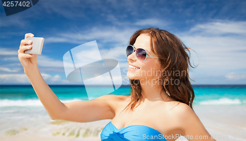 Image of woman in swimsuit taking selfie with smatphone