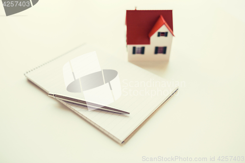 Image of close up of house model, notebook and pencil