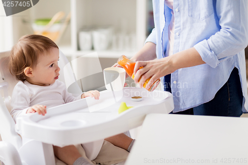 Image of baby and mother pouring juice to cup at home